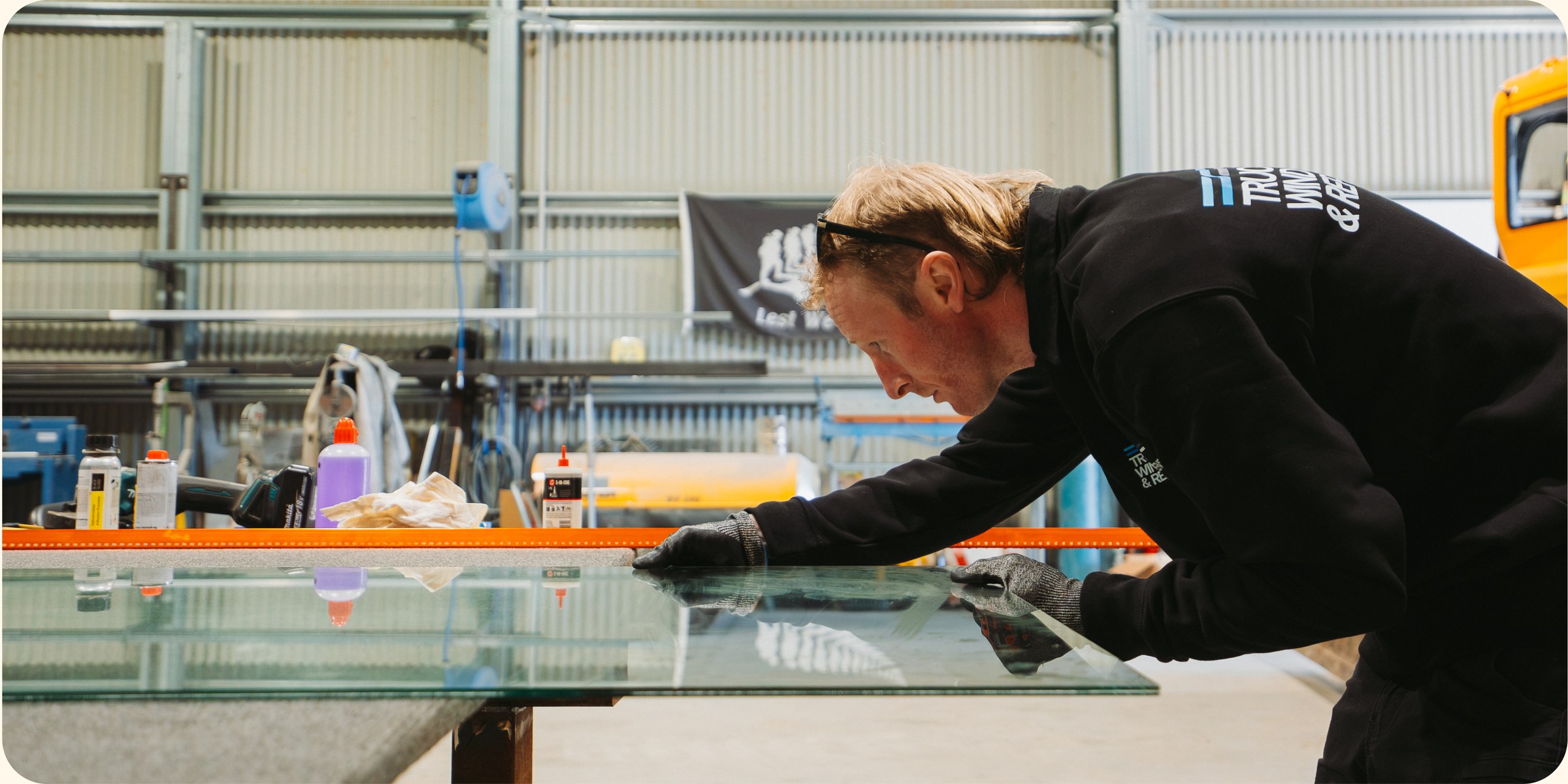 Technician cutting a large pane of glass on the workshop bench