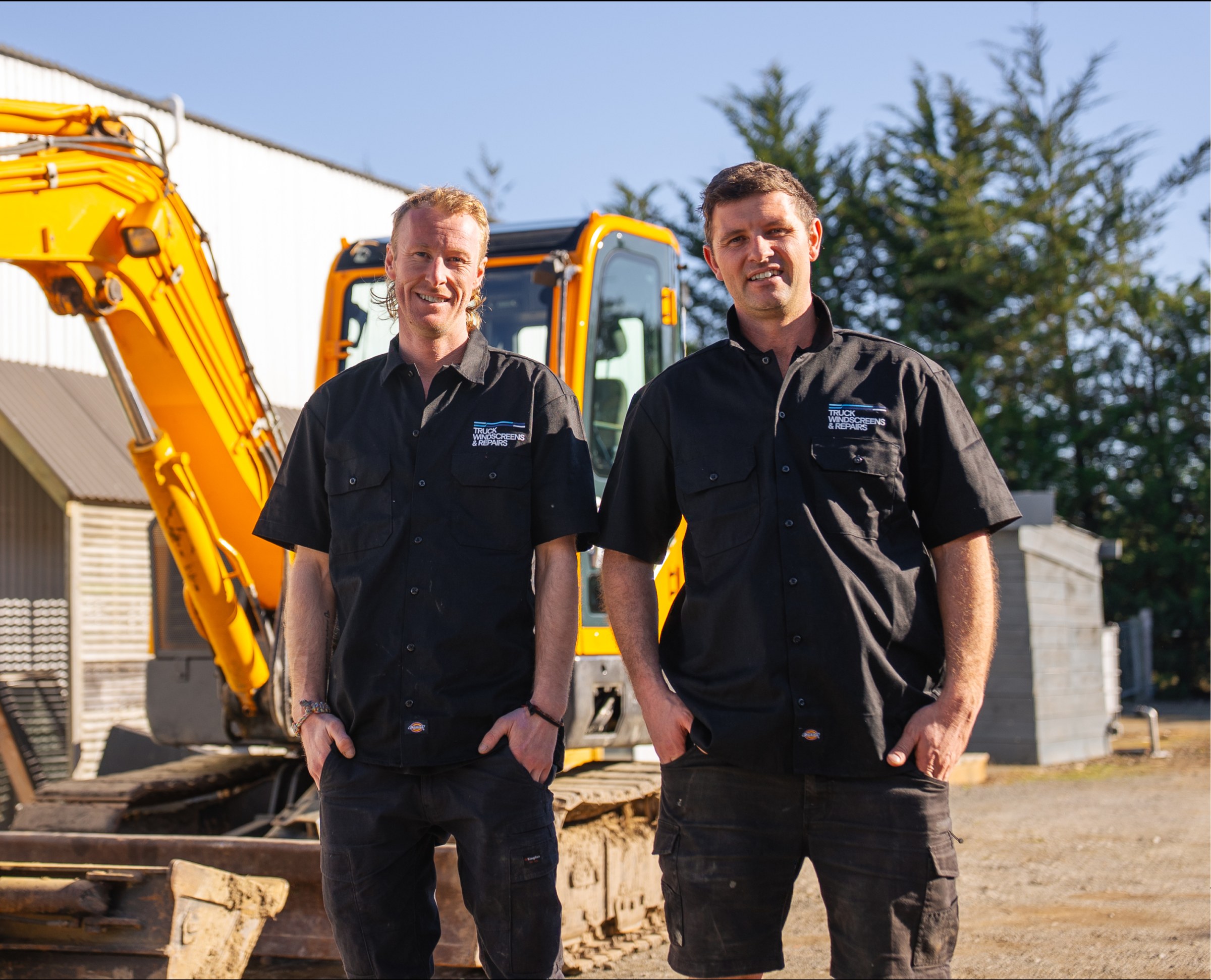 Lyron and Ben in front of an excavator