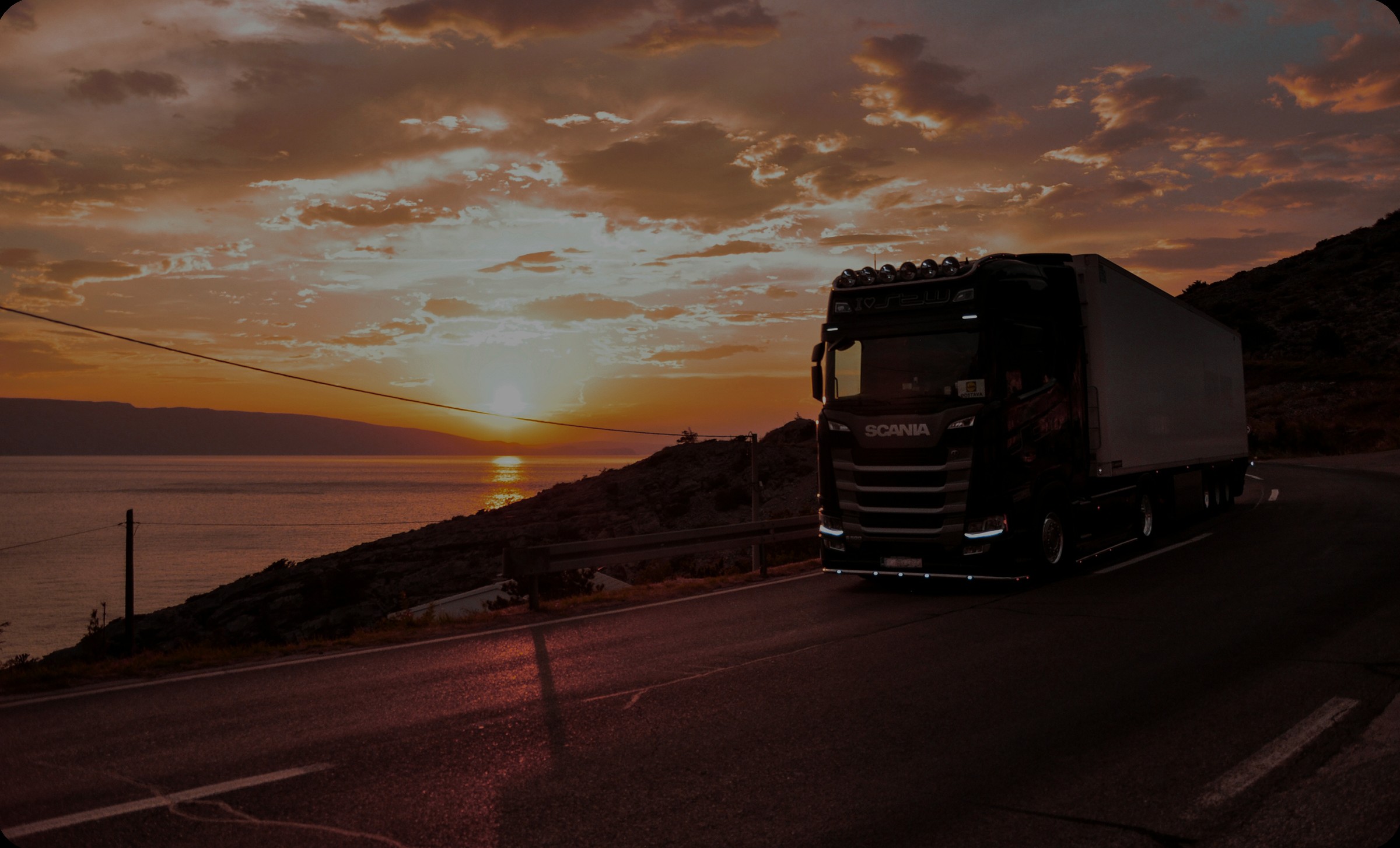 Commercial truck on a coastal road at sunset