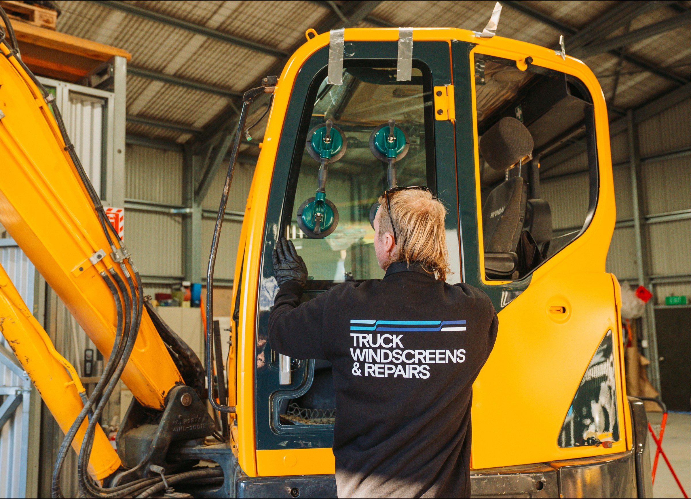 Technician fitting glass to an excavator cab